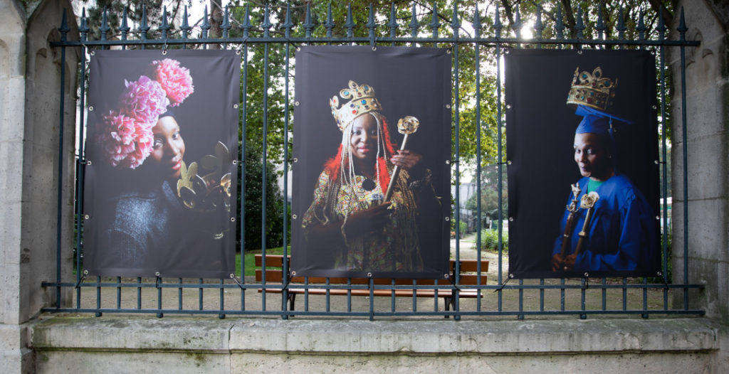 Portraits de femmes prises en charge par la Maison des femmes de Saint-Denis, posant en reines et exposés sur les grilles du jardin de la Basilique Cathédrale.